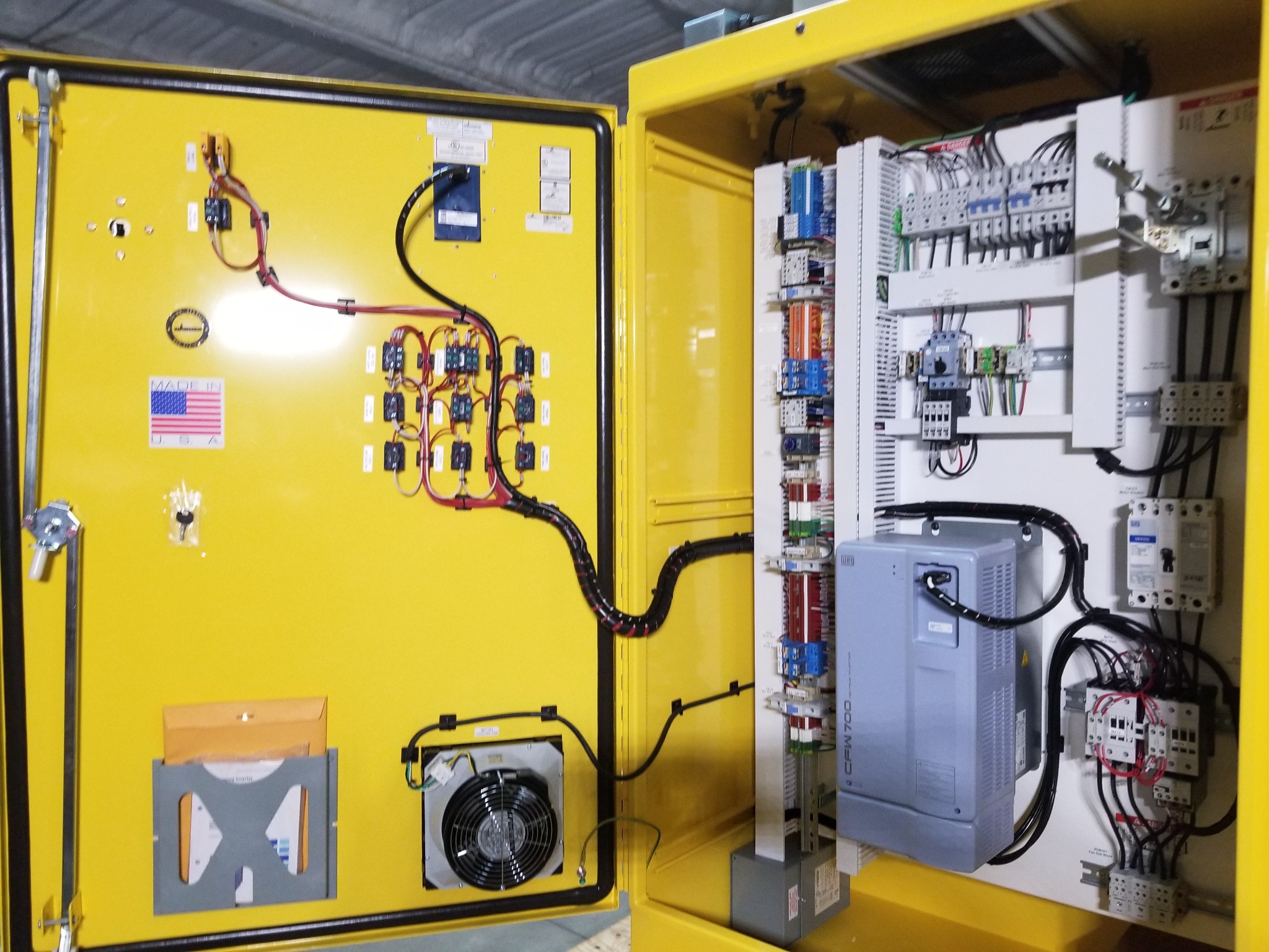 Interior of a custom yellow control cabinet showing electrical components, a drive, and panel wiring