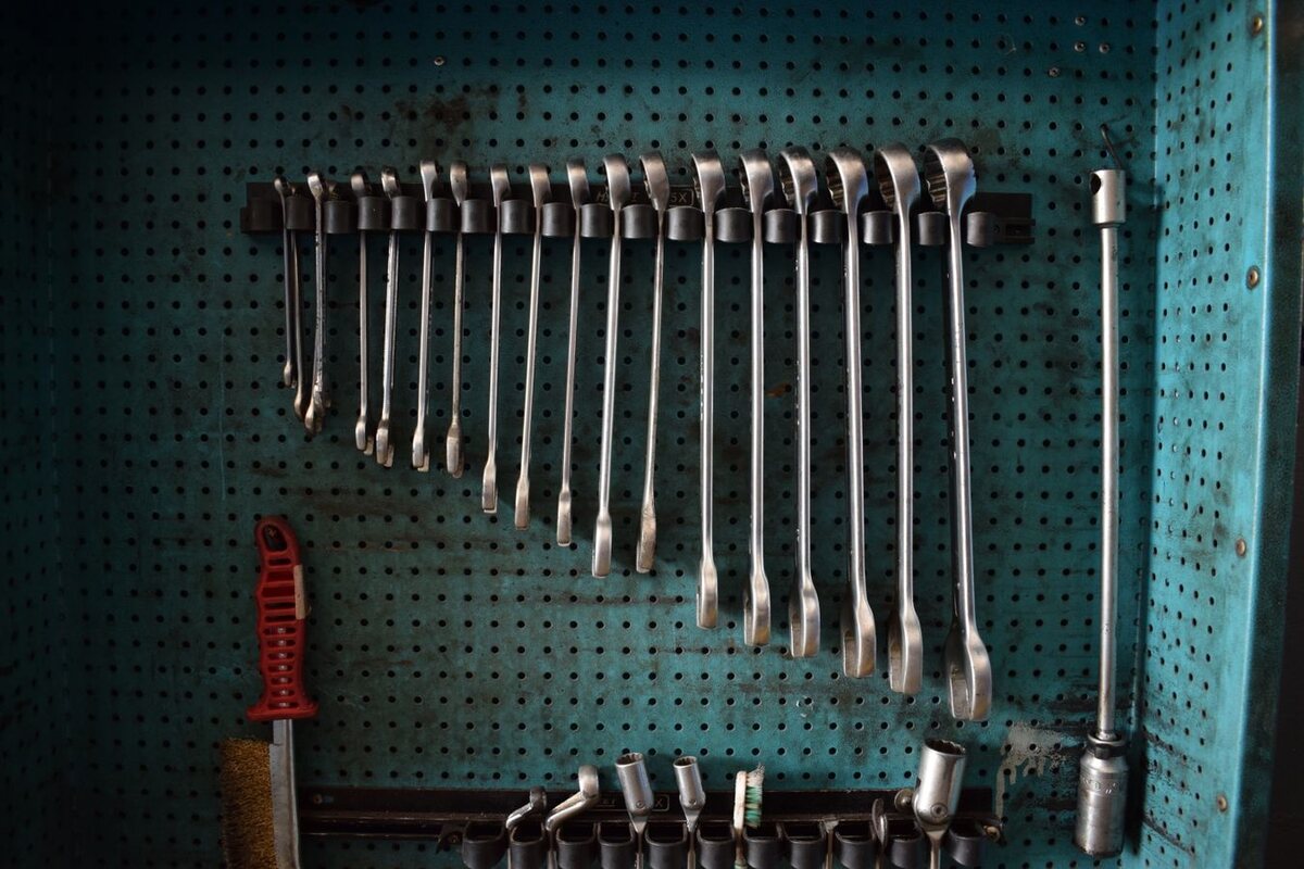 Organized hand tools and wrenches on an industrial workshop wall
