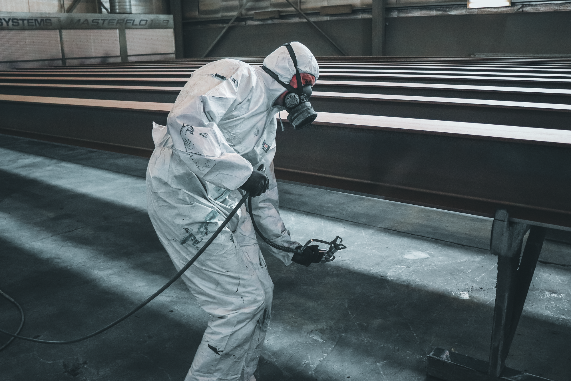 Worker applying an industrial finish to large metal structures in a factory